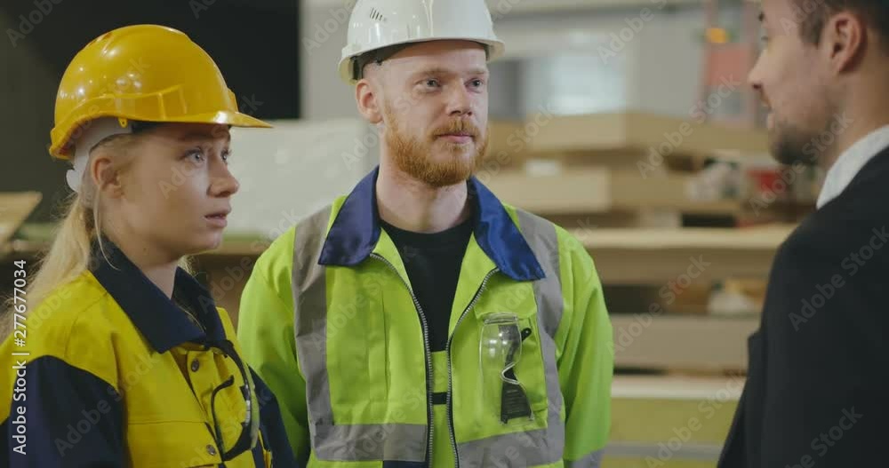 Businessman shaking hands with two factory workers Businessman shaking hands with two factory workers