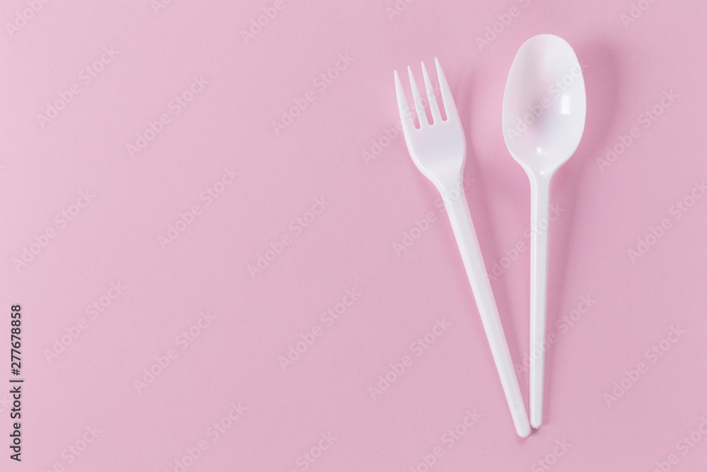pink background with plastic fork and spoon pink background with plastic fork and spoon