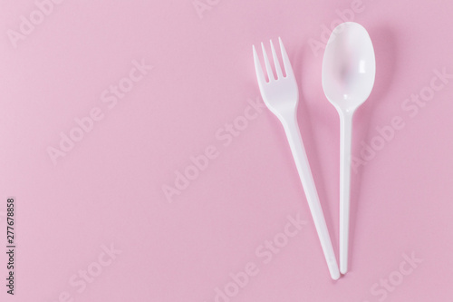 pink background with plastic fork and spoon