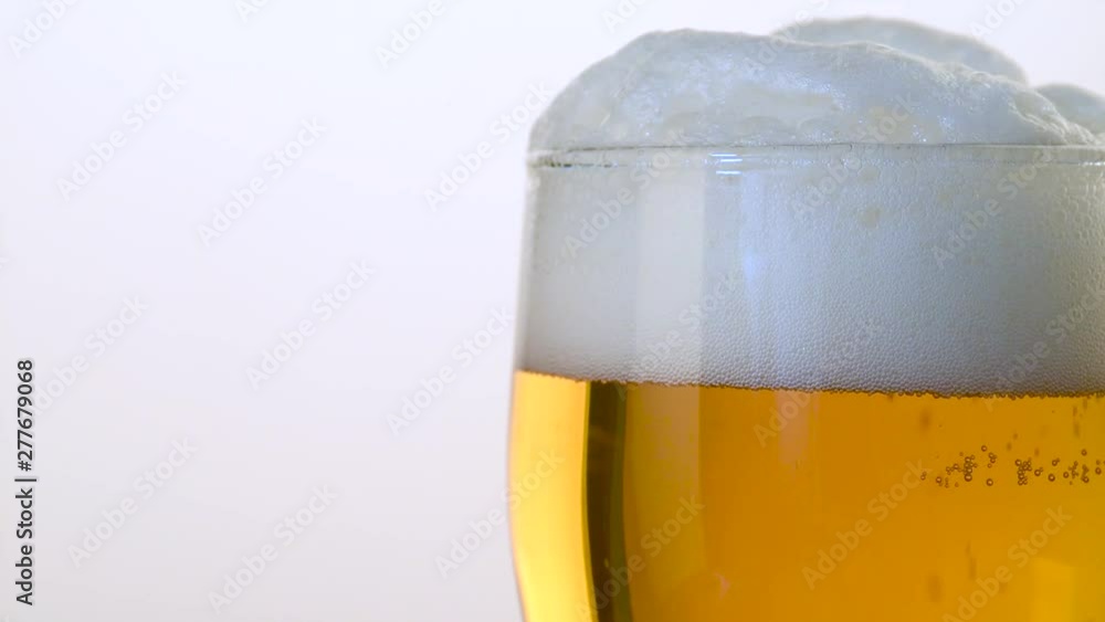 light beer is poured into a glass with foam close-up on a white background light beer is poured into a glass with foam close-up on a white background