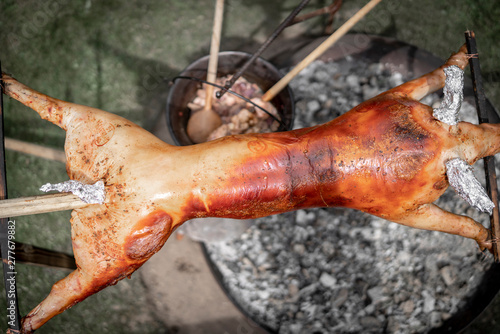 Spanferkel über dem Lagerfeuer gegrillt von einem Wilden auf einer Gartenparty