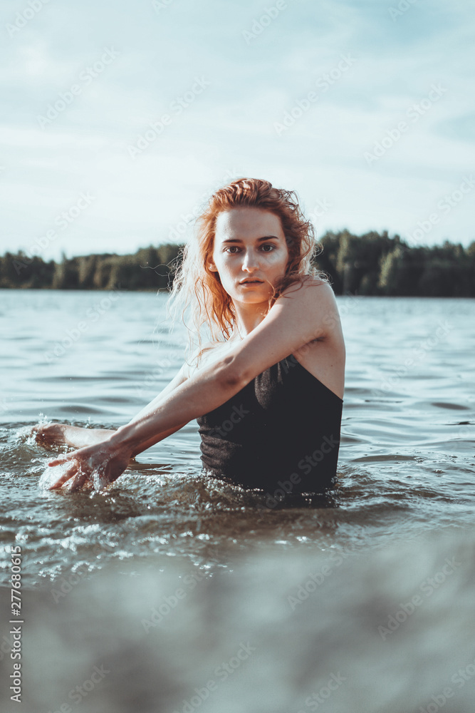 Obraz premium Young beautiful woman standing in the water. Black swimsuit. Vintage style. vertical photo