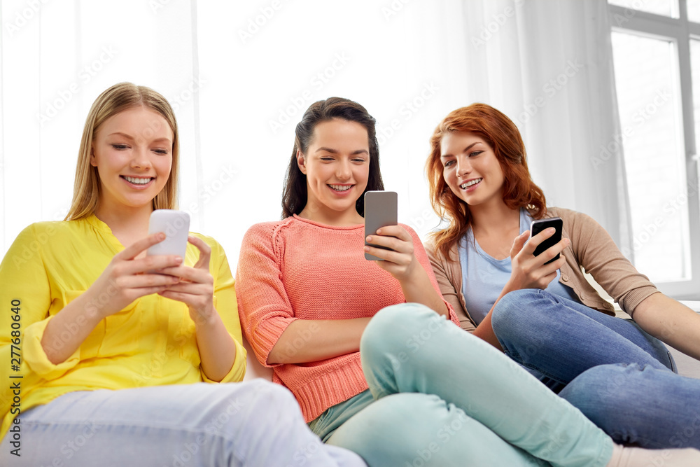 friendship, technology and internet concept - three smiling teenage girls or friends with smartphones at home friendship, technology and internet concept - three smiling teenage girls or friends with smartphones at home