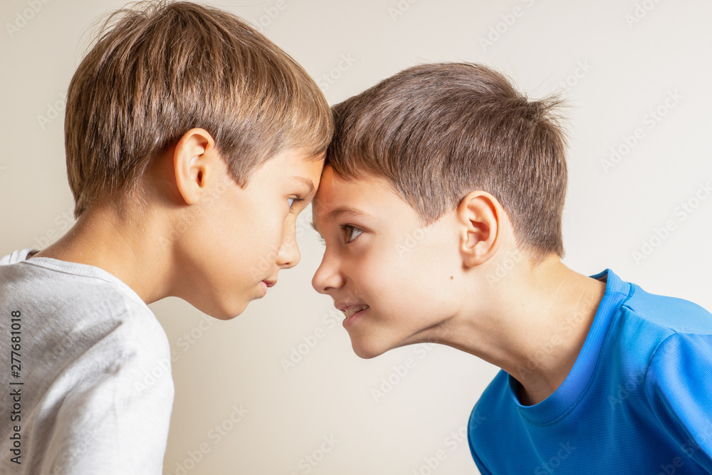 Two angry boys standing face to face, quarreling and looking at each other Two angry boys standing face to face, quarreling and looking at each other