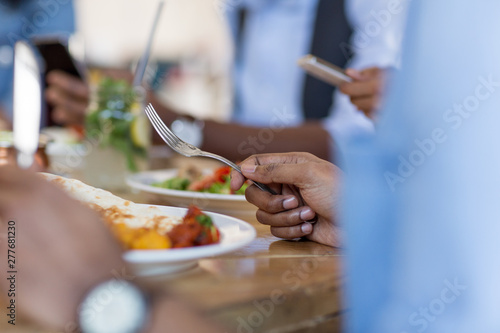 leisure, food and people concept - close up of african american man eating with friends at restaurant