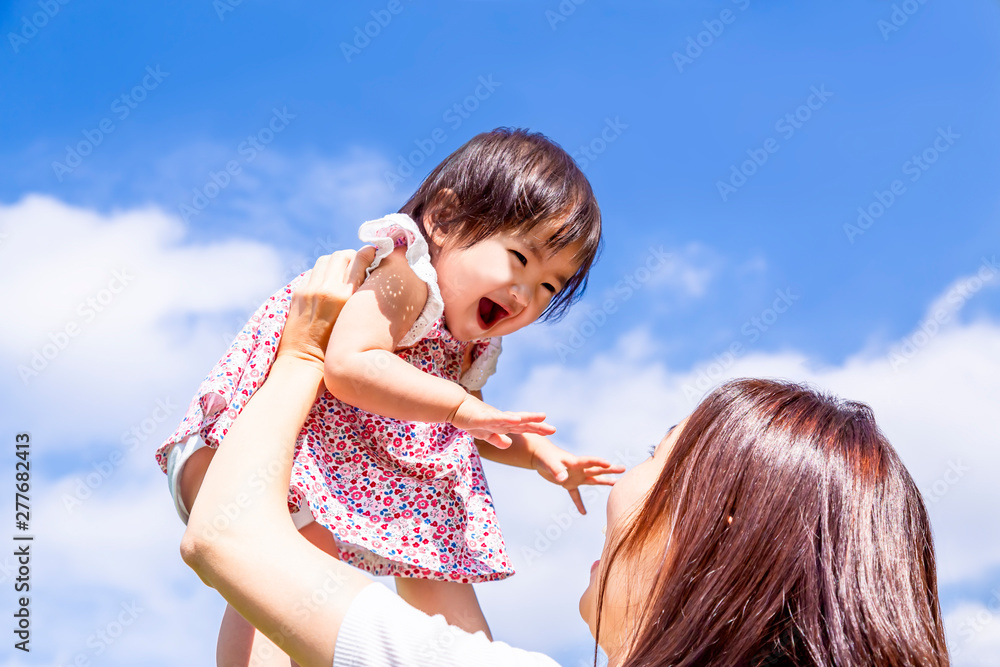Obraz premium 青空の下、赤ちゃんを高い高いをしてあやすお母さん。家族、母子、親子、幸せ、愛、育児、子育てイメージ