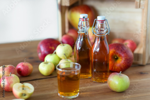 Fototapeta Naklejka Na Ścianę i Meble -  fruits, food and harvest concept - glass and bottles of apple juice or cider on wooden table