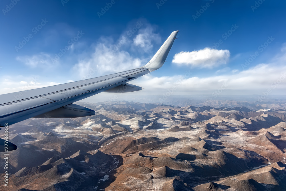 Obraz premium Wing of an airplane with the Himalayas below with its snow topped peaks