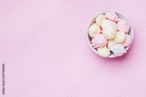 Colored small meringues on a pink background. Flat lay concept. Copy space.