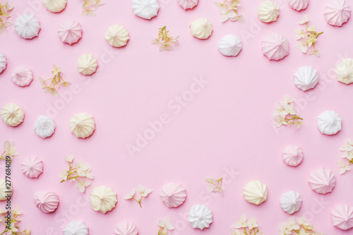 Colored small meringues on a pink background. Flat lay concept. Copy space.