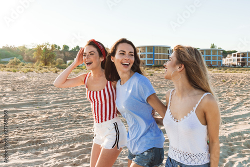 Three happy girlfriends spending fun time at the beach