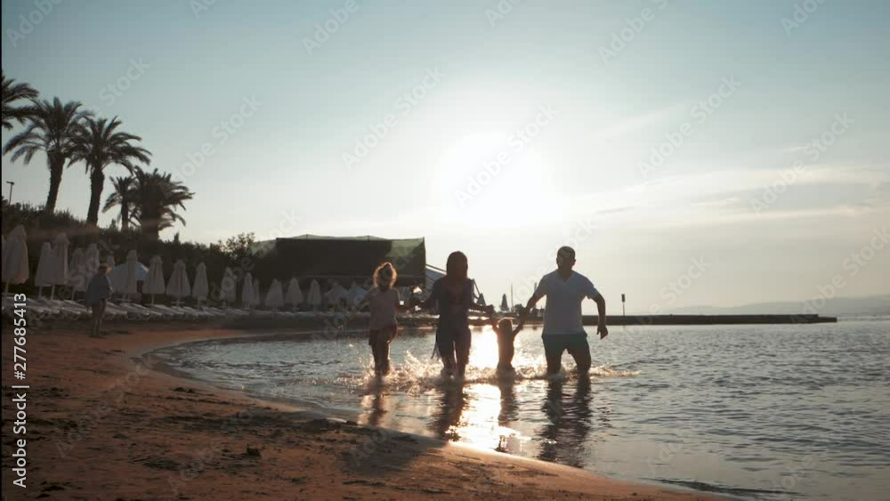 Silhouette of active family having fun and enjoying togetherness on the beach at sunset.