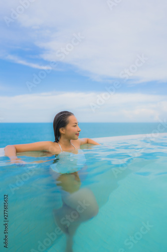 Portrait young asian woman relax smile happy around outdoor swimming pool in hotel resort with sea ocean view © siraphol