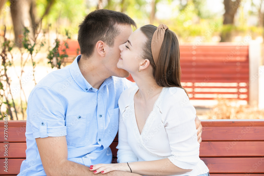Obraz premium Young couple sitting on bench in park.