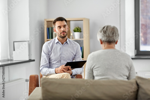 geriatric psychology, mental therapy and old age concept - psychologist with tablet computer listening to senior woman patient at psychotherapy session