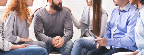 Women comforting stressed man at support therapy photo