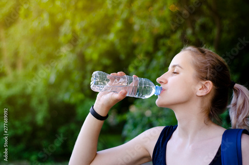 Beautiful girl drinking water after exercise. Playing sport.