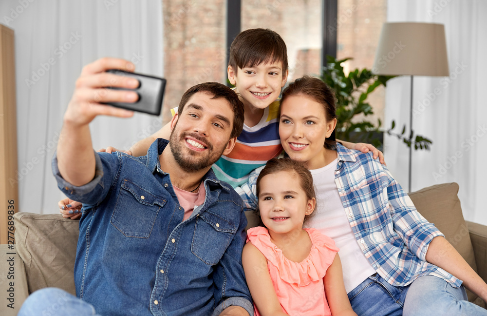 family, technology and people concept - happy father, mother, little son and daughter taking selfie by smartphone at home family, technology and people concept - happy father, mother, little son and daughter taking selfie by smartphone at home
