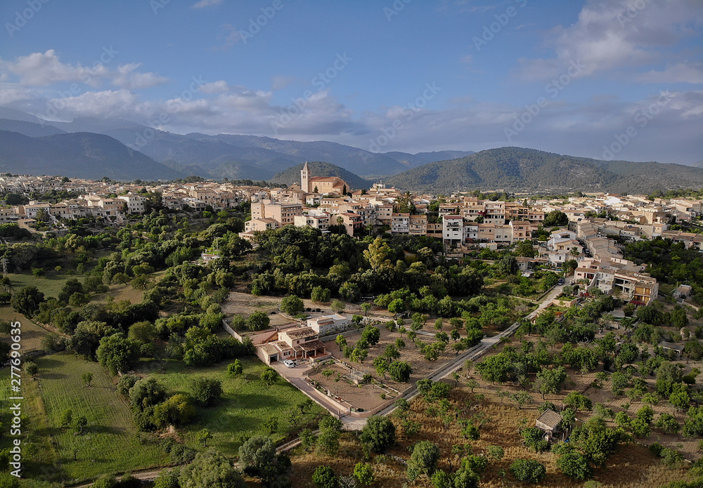 Aerial distant photo drone point of view image Campanet town hillside residential old ancient houses building exterior situated in the northeast of Majorca Island, Spain