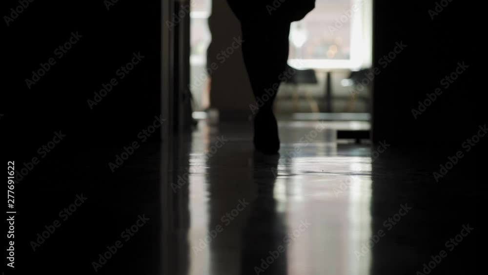 Lockdown backlit shot of unrecognizable woman in high heels walking down office corridor towards camera in slow motion, low angle closeup Lockdown backlit shot of unrecognizable woman in high heels walking down office corridor towards camera in slow motion, low angle closeup