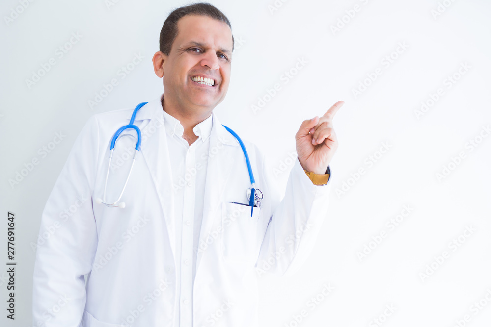 Middle age doctor man wearing stethoscope and medical coat over white background with a big smile on face, pointing with hand and finger to the side looking at the camera. Middle age doctor man wearing stethoscope and medical coat over white background with a big smile on face, pointing with hand and finger to the side looking at the camera.