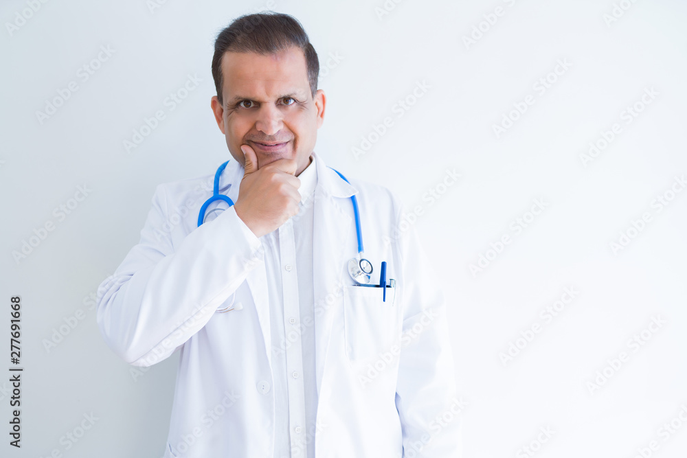 Middle age doctor man wearing stethoscope and medical coat over white background looking confident at the camera with smile with crossed arms and hand raised on chin. Thinking positive. Middle age doctor man wearing stethoscope and medical coat over white background looking confident at the camera with smile with crossed arms and hand raised on chin. Thinking positive.