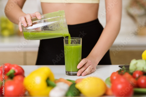 Woman pouring smoothie from blender jar to glass