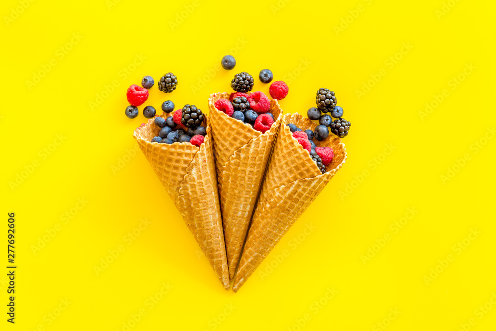 Summer breakfast with fresh berries in waffle cones on yellow background top view Summer breakfast with fresh berries in waffle cones on yellow background top view