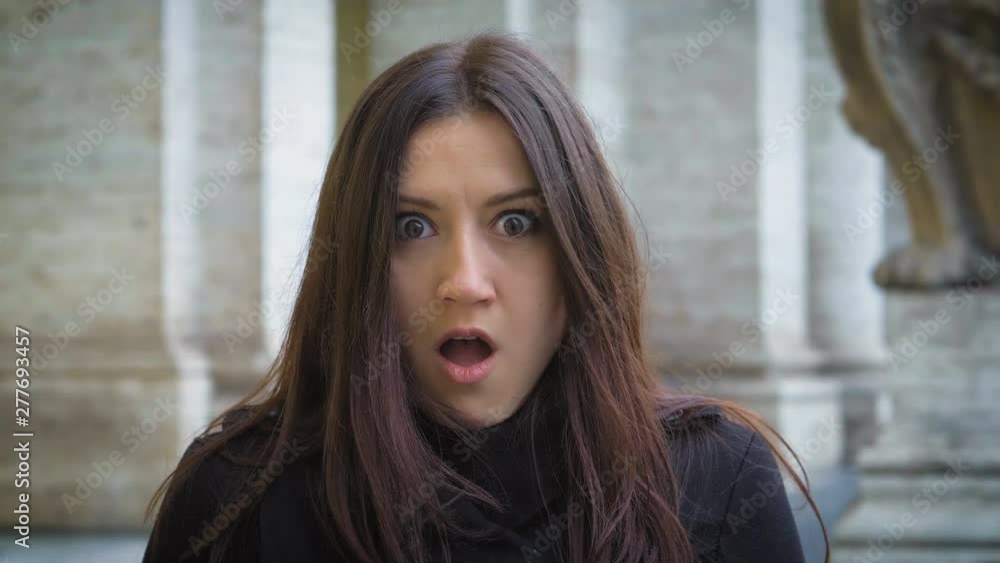 Beautiful young woman looking around seeing the camera and getting scared Beautiful young woman looking around seeing the camera and getting scared