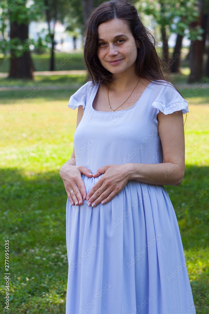 Portrait of beautiful and happy young woman holding heart of hands on her big pregnant belly. Portrait of beautiful and happy young woman holding heart of hands on her big pregnant belly.