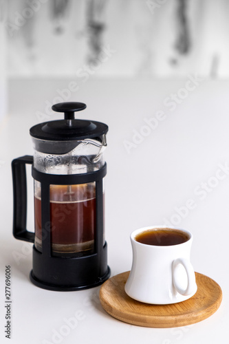 Cup of coffee made with French press is ready to serve, white background.