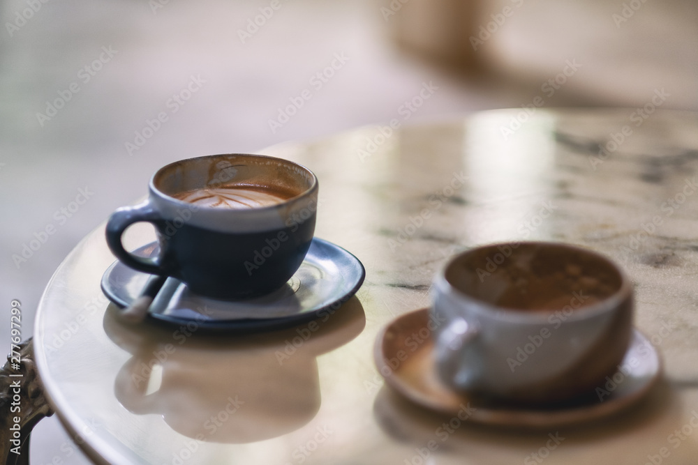 Fototapeta Closeup image of two cups of hot coffee on marble table in cafe