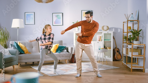 Happy Little Girl Dances with Young Father in the Middle of the Living Room. Happy Family Time, Father and Daughter Dancing at Home. © Gorodenkoff