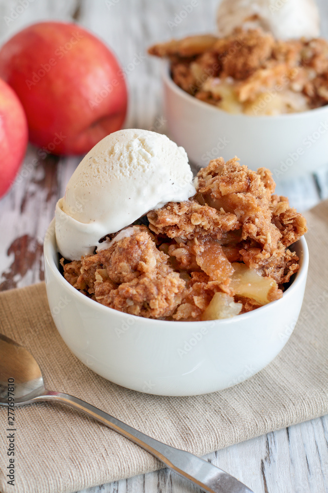 Fresh hot homemade apple crisp or crumble with crunchy streusel topping topped with vanilla bean ice cream. Selective focus with blurred background. Fresh hot homemade apple crisp or crumble with crunchy streusel topping topped with vanilla bean ice cream. Selective focus with blurred background.