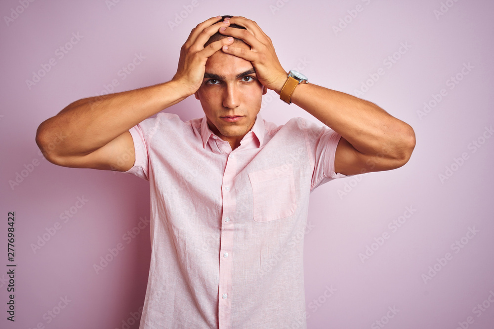 Young handsome man wearing elegant shirt over pink isolated background suffering from headache desperate and stressed because pain and migraine. Hands on head. Young handsome man wearing elegant shirt over pink isolated background suffering from headache desperate and stressed because pain and migraine. Hands on head.