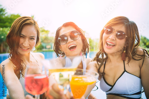 three younger asian woman happiness drinking beverage in waer swimming pool