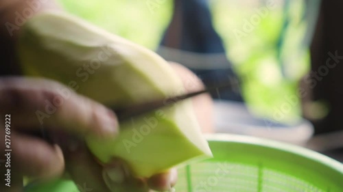 Old lady using knife to cut a winter melon to pieces. Ingredient for cooking