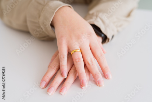 Close up of woman hands showing golden alliance with hands on each other over white table