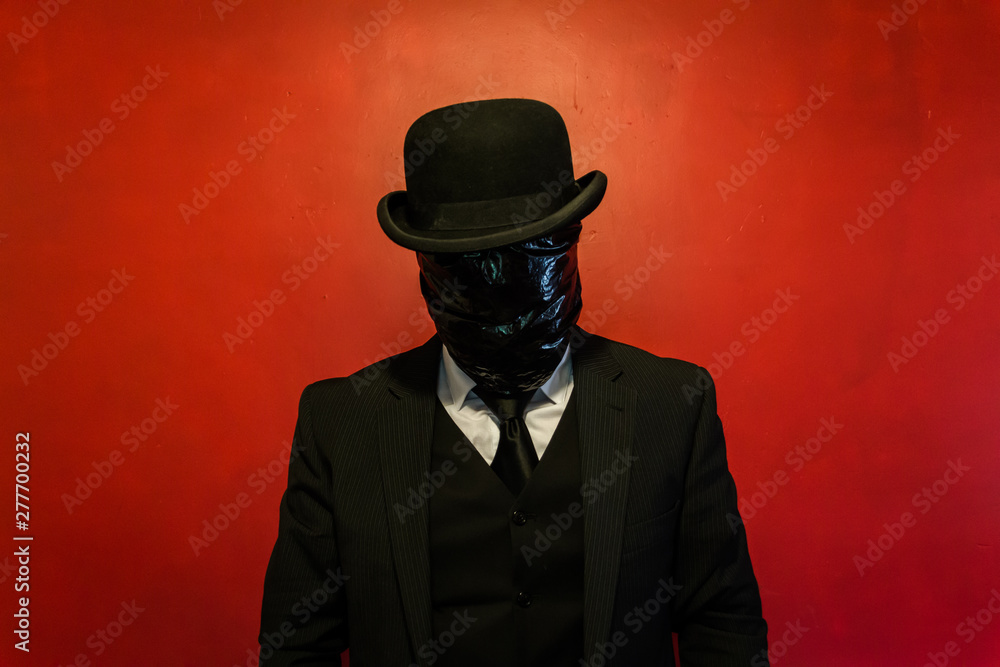 Concept Portrait of Man in Dark Suit and Bowler Hat With Black Plastic Bag Wrapped Over His Face. Horror Movie Murderer. Copy Space for Fear and Death. Dark Stock Photo.
