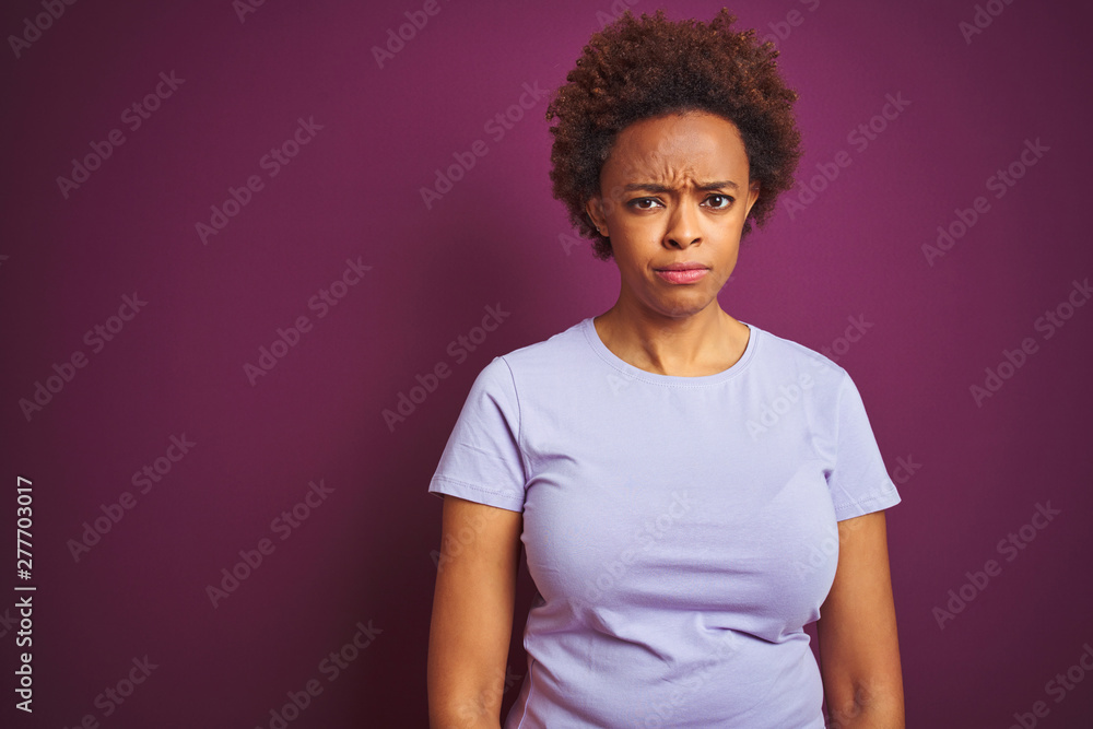 Obraz premium Young beautiful african american woman with afro hair over isolated purple background skeptic and nervous, frowning upset because of problem. Negative person.