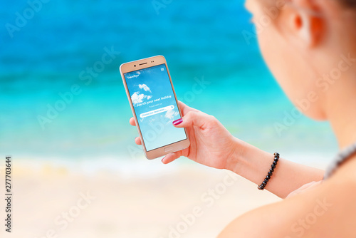 Woman use travel app on smart phoe to find destination. Beach in background. photo