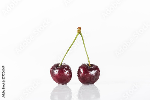 red, fresh, whole and wet cherries on white background with copy space