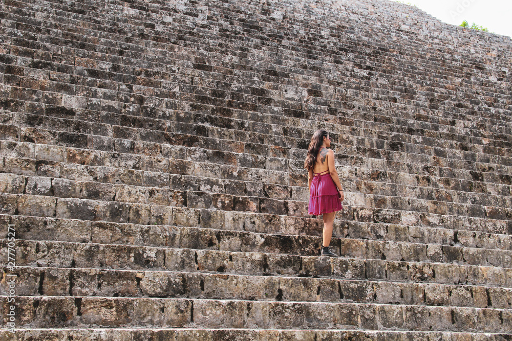 Girl walking on the mayan pyramid stairs in ancient city of Uxmal in Yucatan