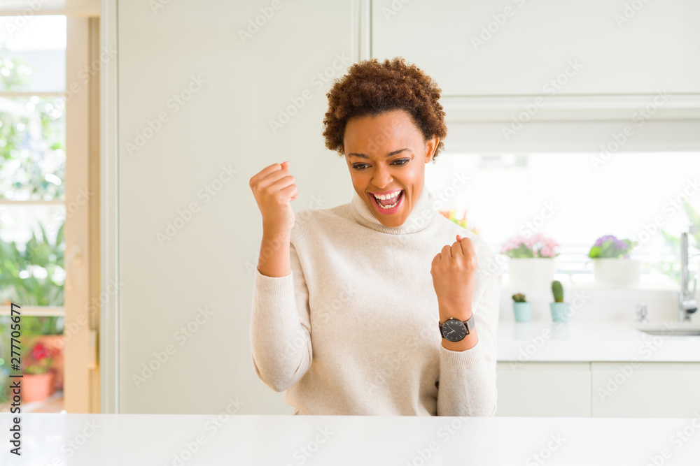 Young beautiful african american woman at home very happy and excited doing winner gesture with arms raised, smiling and screaming for success. Celebration concept. Young beautiful african american woman at home very happy and excited doing winner gesture with arms raised, smiling and screaming for success. Celebration concept.
