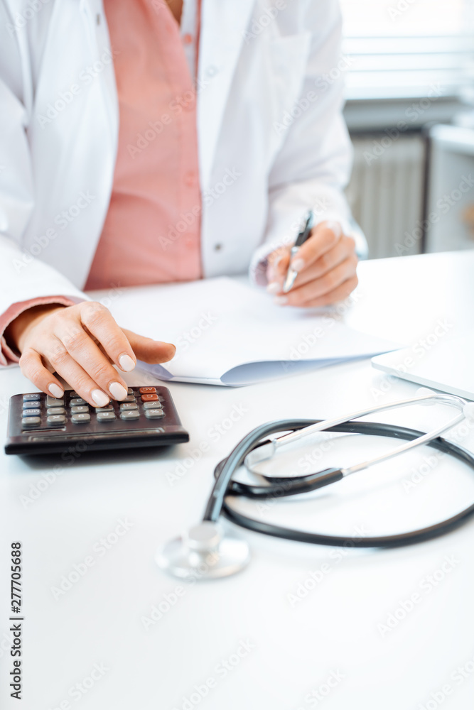 Fototapeta premium Doctor using calculator writing bills and doing bookkeeping
