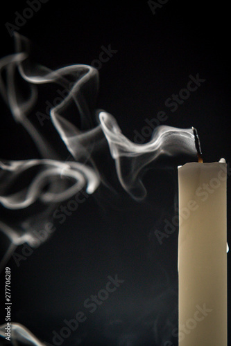 Smoke and extinct candle on a black background
