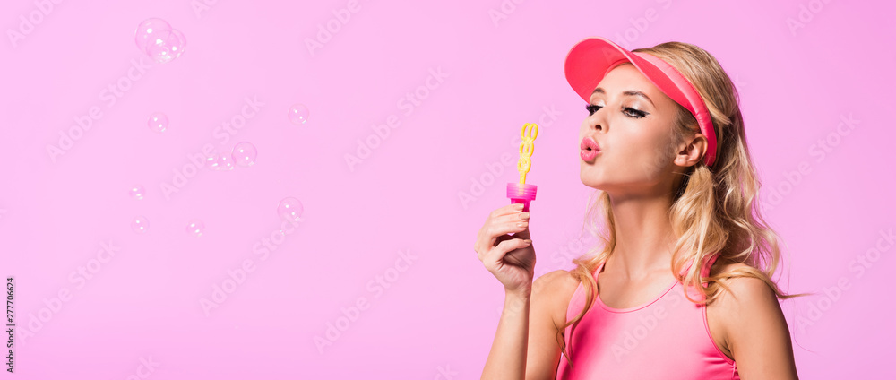panoramic shot of beautiful girl blowing soap bubbles isolated on pink, doll concept