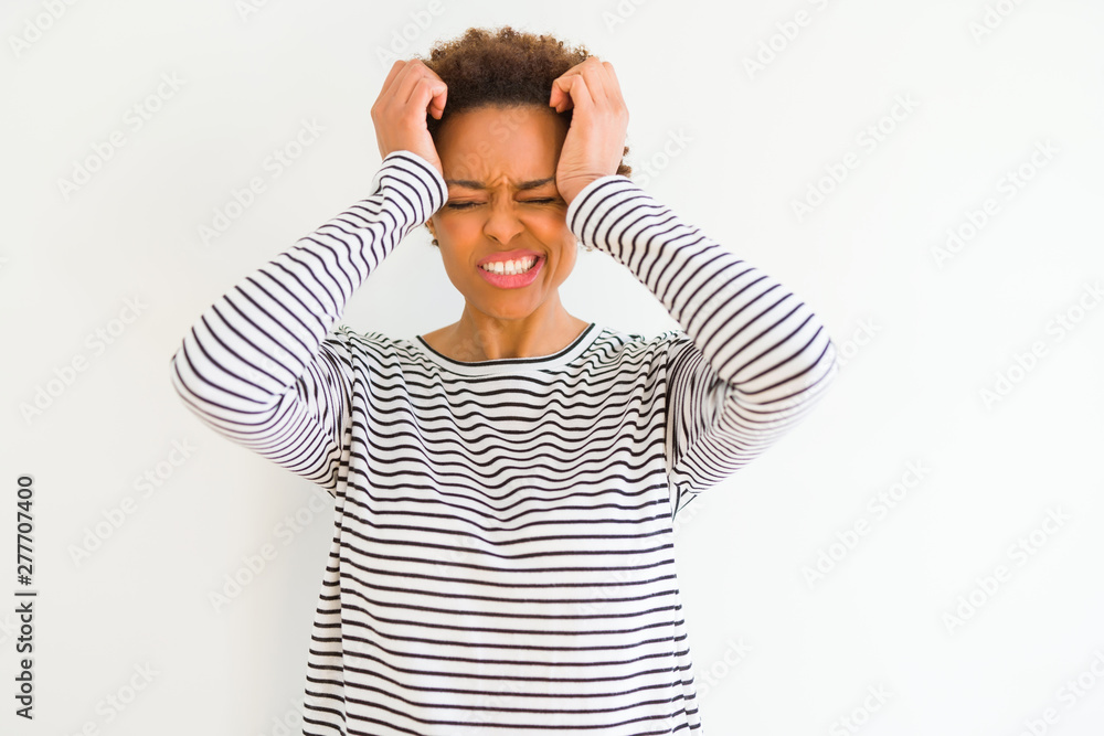 Young beautiful african american woman wearing stripes sweater over white background suffering from headache desperate and stressed because pain and migraine. Hands on head.