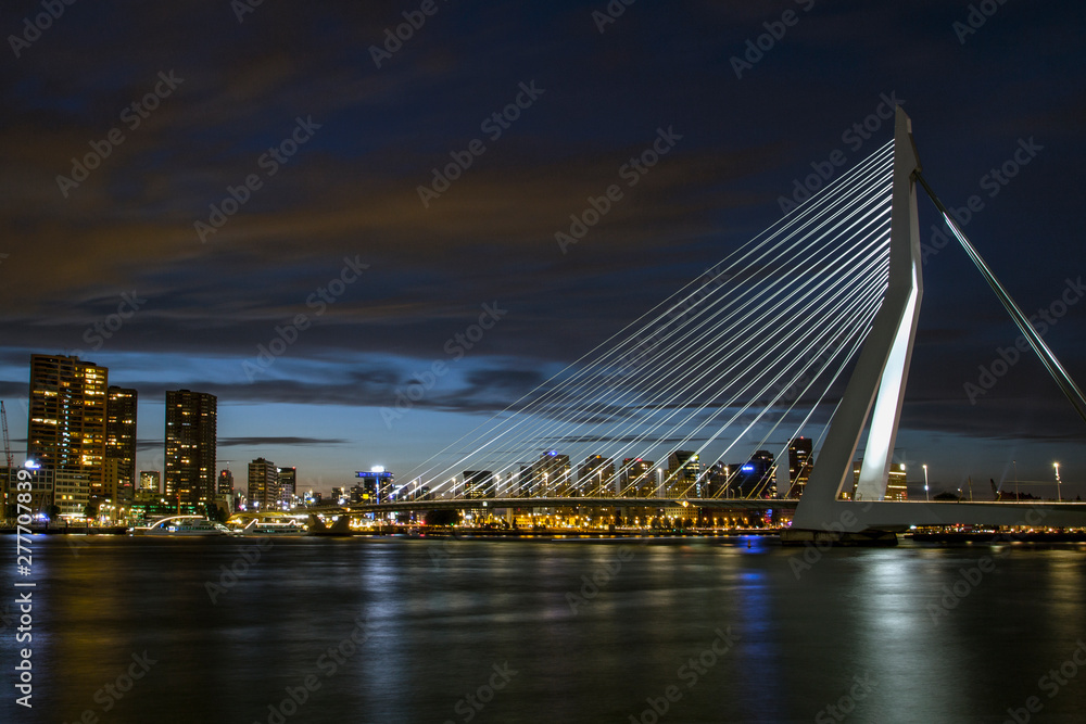 Fototapeta premium A view of the Erasmus Bridge over the the Nieuwe Maas (New Meuse) River . Cityscape at night. Rotterdam, The Netherlands.