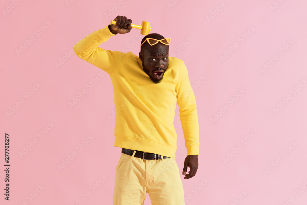 Funny black man beating head with hammer on yellow, portrait Stock Photo |  Adobe Stock